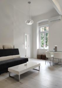 a white living room with a black couch and a table at Luxurios and historic apartment "Shine" - right on the Main Square in Zagreb