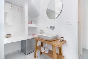 a white bathroom with a sink and a mirror at Central Suites Mykonos in Mýkonos City