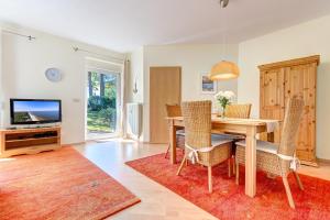 a dining room with a table and chairs and a television at Haus Berlin Loddiner Höft in Loddin