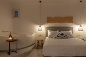 a bedroom with a bed and a bath tub with a bottle of wine at Central Suites Mykonos in Mýkonos City