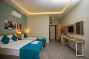 a hotel room with two beds and a desk at Marti Beach Hotel in Kuşadası