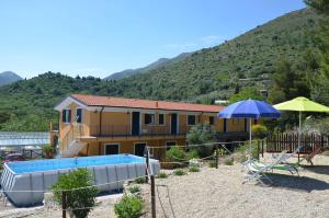 a house with a swimming pool and an umbrella at Agriturismo Tendapiccola in Ceriale