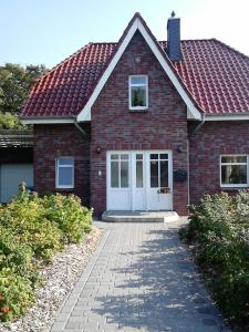 a brick house with a red roof and a driveway at Strandrose in Friedrichskoog