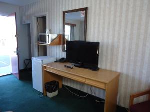 um quarto com uma secretária e uma televisão em Kingsway Inn em Thunder Bay
