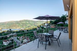 a patio with a table and chairs and an umbrella at Merck Villa Gerês in Rio Caldo