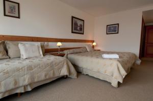 a hotel room with two beds and two lamps at Hotel Huemul in San Carlos de Bariloche