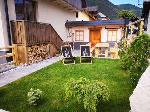 a backyard with two lawn chairs and a table at Hiša Pod gorami**** - house with wellness in Kranjska Gora