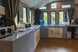 a large kitchen with a counter with a microwave at Amantra homestay & village in Suratthani