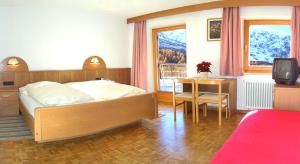 1 dormitorio con cama, mesa y TV en Hotel Alpenhof, en Solda