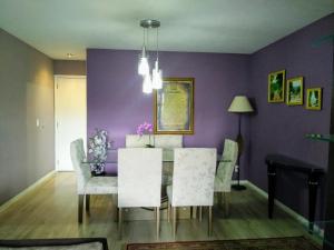 uma sala de jantar com uma mesa e cadeiras e paredes roxas em Apartamento Vila DR - Barra da Tijuca,prox Jeunesse,Arenas,Rio Centro,praias, Shopping no Rio de Janeiro