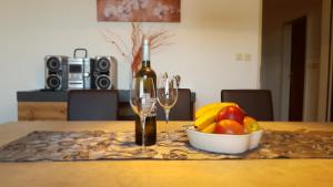 a bottle of wine and a bowl of fruit on a table at Holiday home Elis in Fažana