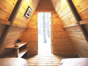 a bedroom in a log cabin with a large window at Hoya Surf Camp - Activités + logements in Biscarrosse