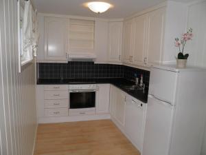 a white kitchen with white appliances and black counter tops at Fjellheim in Herlø