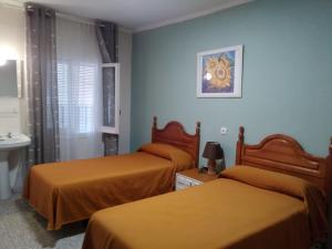 オカーニャにあるHostal Ávilaのベッド2台とシンク付きのホテルルームです。
