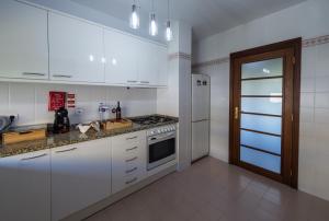 a kitchen with white cabinets and a stove top oven at CreaConfort - Casa do Rio in Rio Mau