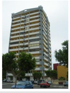 wysoki budynek z samochodami zaparkowanymi na parkingu w obiekcie APARTAMENTO CERCA DE LA PLAYA w mieście Aguadulce