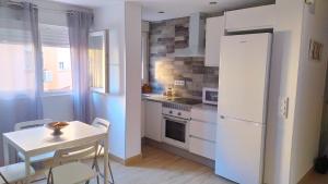 cocina con mesa y nevera blanca en Loft 500 metros de la playa, en Cádiz