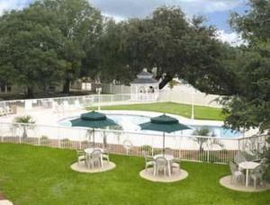 a pool with tables and chairs in a yard at Motel 6-Jacksonville, NC in Jacksonville