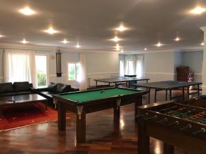 una sala de estar con mesas de ping pong y sofás en Chateau du Loire Apartamento, en Campos do Jordão