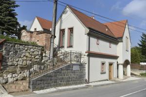 a white house with a stone wall next to a street at Penzion Dobré časy in Valtice