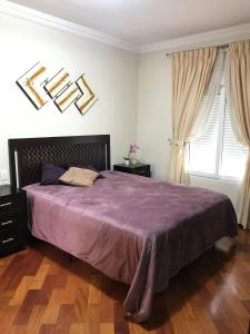 1 dormitorio con 1 cama grande con manta morada en Chateau du Loire Apartamento, en Campos do Jordão