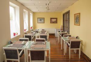 a dining room with tables and chairs and windows at Breeze Guest House in Bootle
