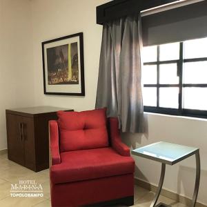 
a red chair sitting in a room next to a window at Hotel Marina Topolobampo in Topolobampo
