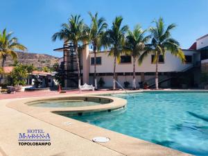 a swimming pool in front of a building with palm trees at Hotel Marina Topolobampo in Topolobampo