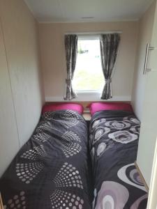 a small room with two beds and a window at Swanage Bay View caravan in Swanage