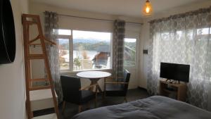 a bedroom with a bed and a table and a window at Apart Costanera in Villa Pehuenia