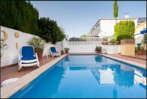 a swimming pool with two blue chairs and a house at GRAN ADOSADO EN ZONA TRANQUILA CON PISCINA PRIVADA solo familias in Gandía