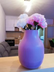 um vaso roxo com flores cor-de-rosa sobre uma mesa em Apartma F&M em Bovec