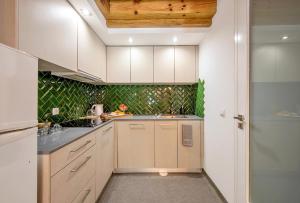 a kitchen with white cabinets and green tiles at Wake Up Famalicão in Vila Nova de Famalicão