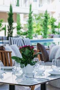 a table with glasses and a vase with flowers on it at Elysia Park in Paphos