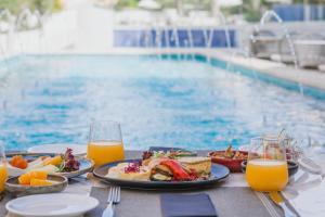 a table with plates of food next to a swimming pool at Elysia Park in Paphos