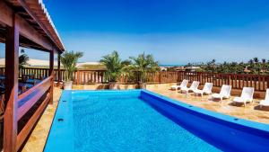 a swimming pool on a patio with chairs and a house at Mini Hotel Dunas in Jericoacoara