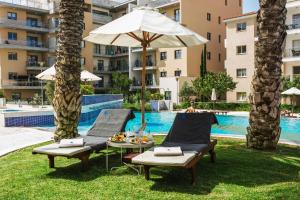 a pool with two chairs and a table and an umbrella at Elysia Park in Paphos