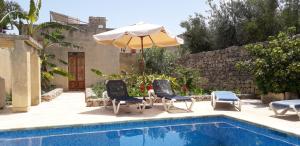 une terrasse avec 2 chaises, un parasol et une piscine dans l'établissement Tal-Masklu farmhouse, à L-Għarb