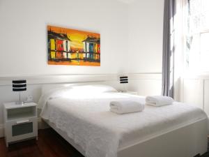 um quarto com uma cama branca e uma pintura na parede em Museum House no Funchal