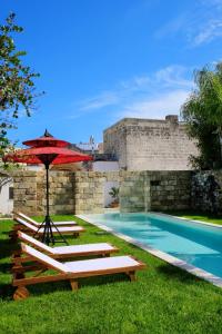 - une piscine avec 2 chaises longues et un parasol dans l'établissement Masseria delle Pecore, à Specchia