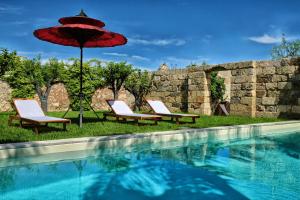 - deux chaises et un parasol à côté de la piscine dans l'établissement Masseria delle Pecore, à Specchia