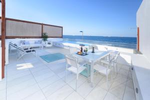 a patio with a table and chairs and the ocean at Villa Marina, Sol y Sal in Las Palmas de Gran Canaria