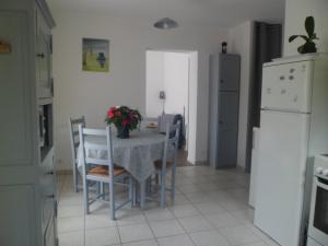 een keuken met een tafel, stoelen en een koelkast bij maisonnette entre forêt et occéan in Vendays-Montalivet +6 foto's