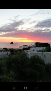 um pôr-do-sol sobre o oceano com edifícios brancos e árvores em La Rosamarina em Stromboli