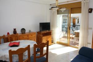 a living room with a dining room table and a television at Adosado Peñisol Inmomart in Peniscola