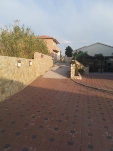 a brick sidewalk with a stone wall and a street at Vila Murvica in Pag