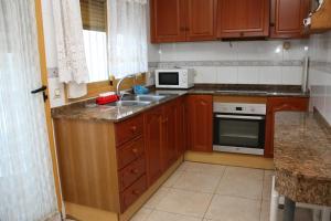a kitchen with wooden cabinets and a sink and a microwave at Adosado Peñisol Inmomart in Peniscola