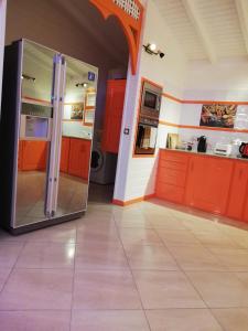 cocina con armarios naranjas y nevera grande en Résidence Clémentine Villa Passion en Grand-Bourg