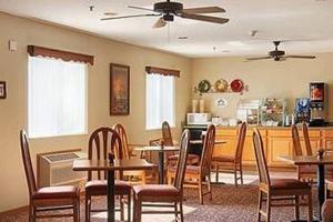 a dining room with tables and chairs and a kitchen at Capri Inn & Suites - Beatrice in Beatrice
