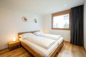 1 dormitorio con 1 cama grande y ventana en Casa Miraselva, en Flims